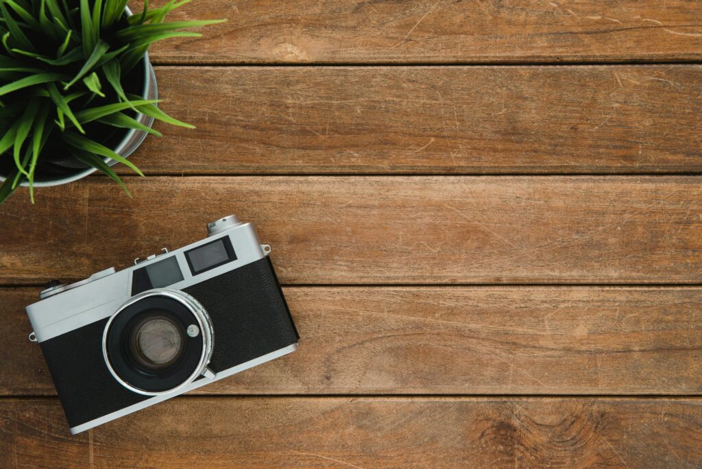 Hakkımızda Retro camera and potted plant on wooden surface with copy space.