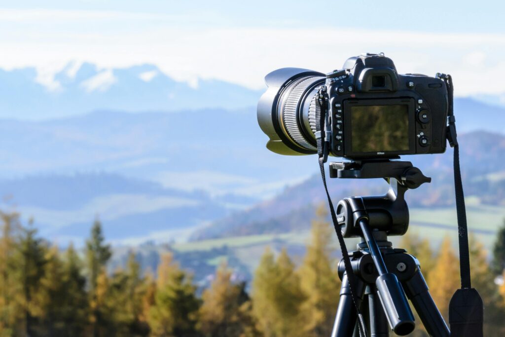 Anasayfa DSLR camera on tripod capturing a stunning mountain view on a clear day.